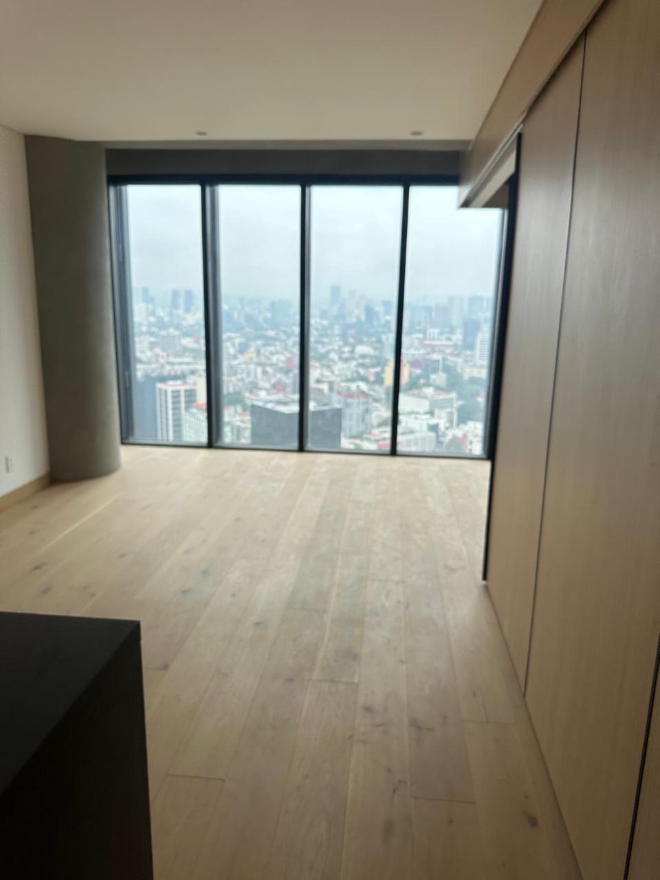 Estancia con ventanales de piso a techo y vista a la ciudad
